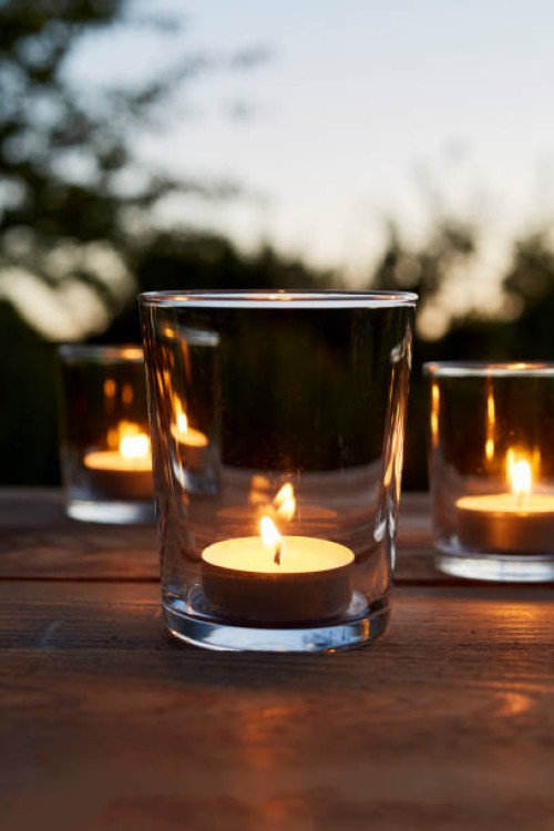 lit tea light candles in glasses on table in garden during sunset - garden decoration stock pictures, royalty-free photos & images