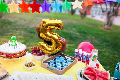 little boy hiding behind golden balloon at laid birthday table - garden decoration stock pictures, royalty-free photos & images