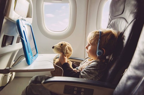 little boy sitting on an airplane watching something on digital tablet - travel stock pictures, royalty-free photos & images