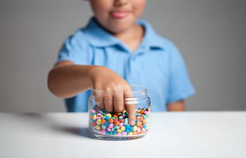 little boy taking candy from jar - junk food stock pictures, royalty-free photos & images