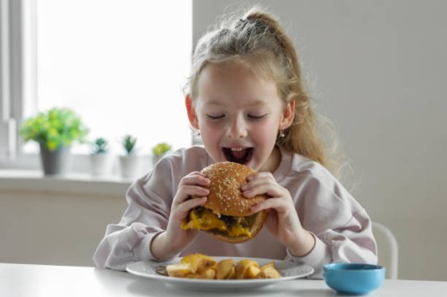 little girl eating a big burger - junk food stock pictures, royalty-free photos & images