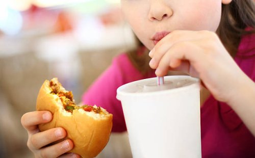 little girl eating burger and drinking soda. - junk food stock pictures, royalty-free photos & images
