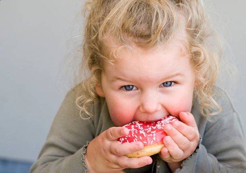 little girl eating jelly-glazed donut with sprinkles - junk food stock pictures, royalty-free photos & images