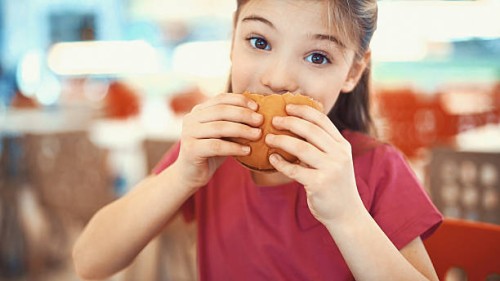 little girl enjoying a burger. - junk food stock pictures, royalty-free photos & images
