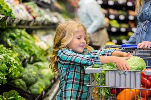 little girl helping mother shop for produce in grocery store - food stock pictures, royalty-free photos & images
