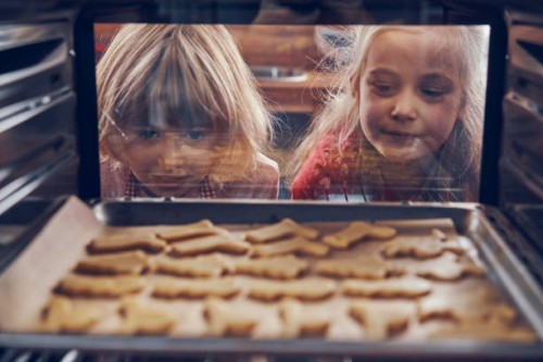 little girls waiting for christmas cookies to bake in the oven - food stock pictures, royalty-free photos & images