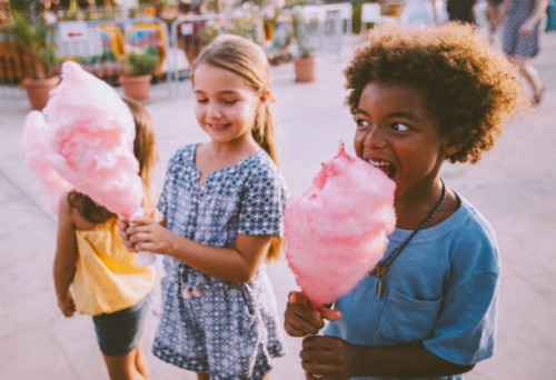 little multi-ethnic children eating cotton candy at amusement park - food stock pictures, royalty-free photos & images
