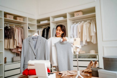 living broadcast about fashion clothes. smiling female choosing clothes outfit with her subscribers on live streaming by phone in the closet - fashion stock pictures, royalty-free photos & images