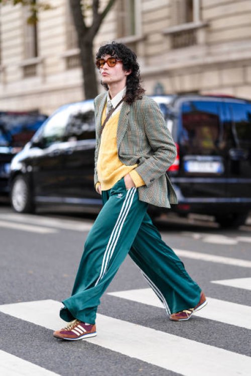 Loic Hornekcer wears dark brown sunglasses, white buttoned up long sleeve shirt, light yellow knit sweater light green tie, light green pattern...