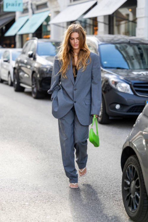 Lois Schindler wears grey oversized striped suit, green bag outside Rotate during the Copenhagen Fashion Week Spring/Summer 2024 on August 10, 2023...