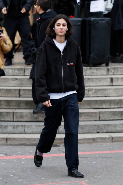 Loli Bahia wears black denim Stüssy jacket, white t-shirt, dark blue jeans, black loafaers, outside Sacai, during the Menswear Fall Winter 2025/2026...