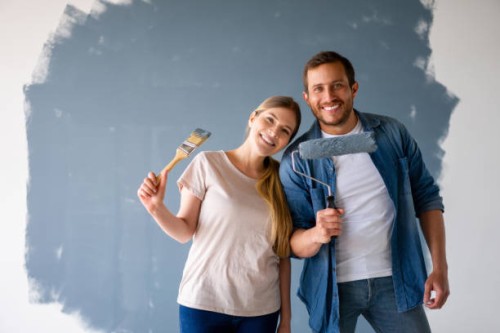 loving couple looking very happy renovating their house and painting the walls - home decoration stock pictures, royalty-free photos & images