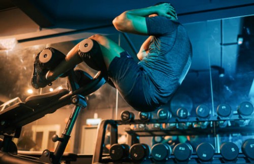 low angle view asian indian macho male athlete sit -ups workout at gym at night with weight bench - home decoration stock pictures, royalty-free photos & images