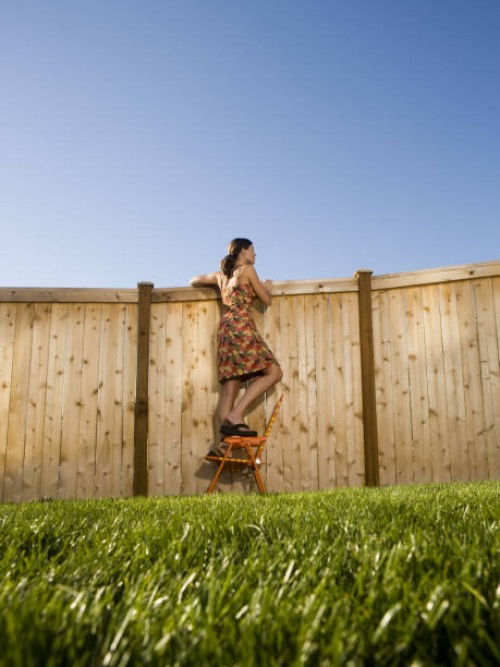low angle view of a woman peeking over a wooden fence - garden decoration photos et images de collection