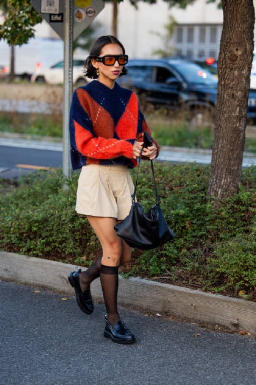Lumia Nocito wears cashmere in red blue, beige shorts, black bag outside COS on September 12, 2023 in New York City.