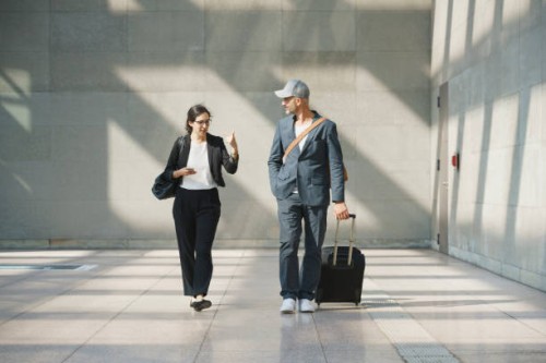 male and female business colleagues talking while walking at airport - fashion photos et images de collection