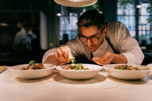 male chef plating food in plate while working in commercial kitchen - food stock pictures, royalty-free photos & images