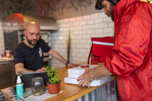 male delivery person, picking up the food at the fast food restaurant for delivery - junk food stock pictures, royalty-free photos & images