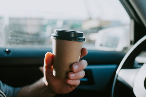 male hand with craft coffee in the car. disposable dishes, coffee on the road while driving. - junk food stock pictures, royalty-free photos & images