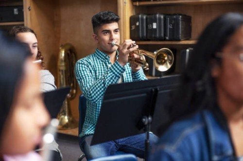 male middle eastern ethnicity student practicing trumpet with friends in school orchestra band - concert stock pictures, royalty-free photos & images