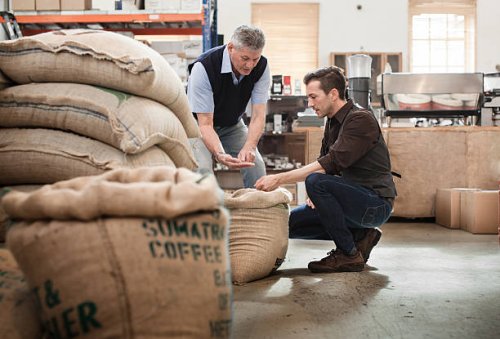 male owner of a coffee roasting business talking with worker - coffee stockfoto's en -beelden