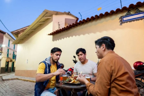 male traveler friends eating on outdoors restaurant in cusco, peru - junk food stock pictures, royalty-free photos & images