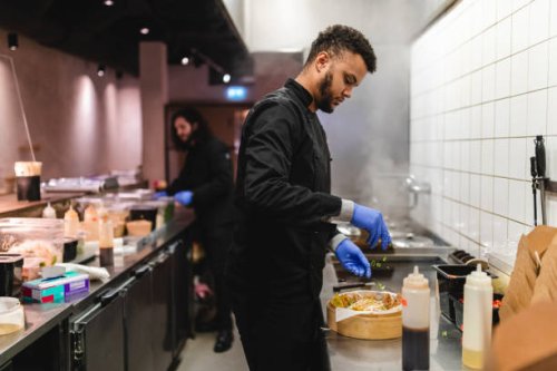 male waiter sprinkling scallion on dumplings in bowl over kitchen counter at restaurant - junk food stock pictures, royalty-free photos & images