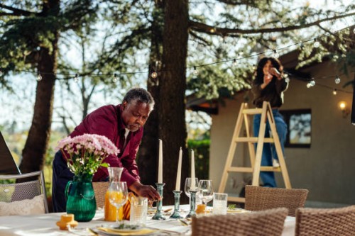 man and woman decorating table and yard for outdoors party - garden decoration stock pictures, royalty-free photos & images