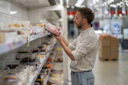 man buying choosing cake in supermarket packaged in plastic container in hypermarket. - junk food stock pictures, royalty-free photos & images