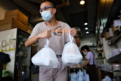 Man carries bags containing takeaway meals in Hong Kong on July 29 after new social distancing measures came into effect which include restaurants...