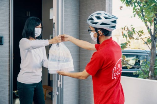 man delivering food to a mature woman while practicing social distancing measures - junk food stock pictures, royalty-free photos & images