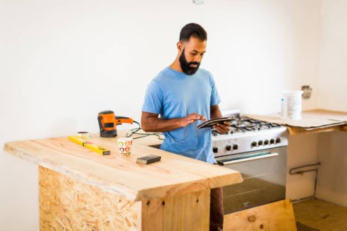man doing diy in kitchen with tablet computer - home decoration stockfoto's en -beelden