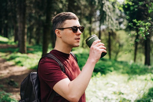 man drinking from a travel mug while exploring a forest trail - junk food stock pictures, royalty-free photos & images