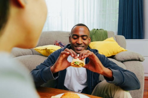 man eating chicken burrito, wide shot pov. - junk food stock pictures, royalty-free photos & images