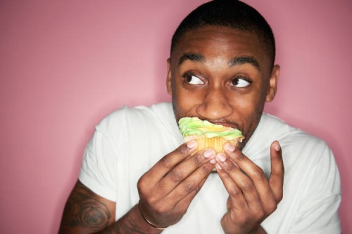 man eating cupcake - junk food stock-fotos und bilder