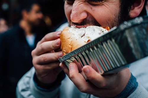 man eating hot dog on the streets - junk food stock pictures, royalty-free photos & images