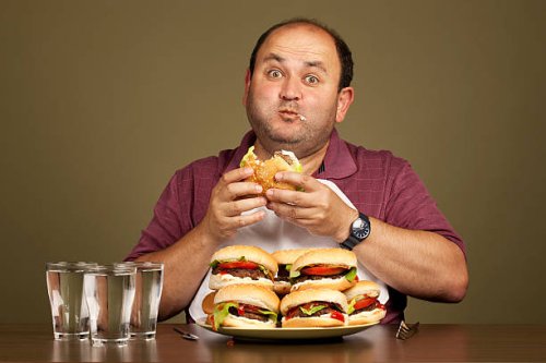 man eating many burgers - junk food stock pictures, royalty-free photos & images