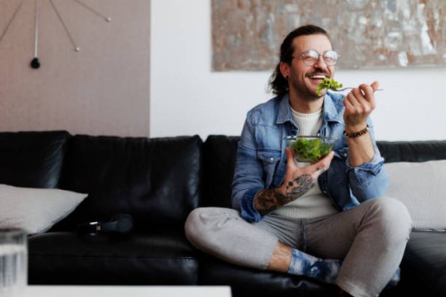 man eating salad and drinking water at home - food stockfoto's en -beelden