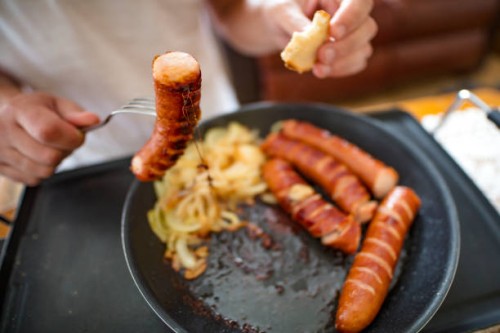 man eating sausages, close-up for breakfast on hot electric hob - junk food stock pictures, royalty-free photos & images
