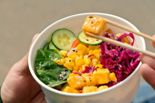 man eating vegan poke with tofu outdoors in summer - junk food stock pictures, royalty-free photos & images
