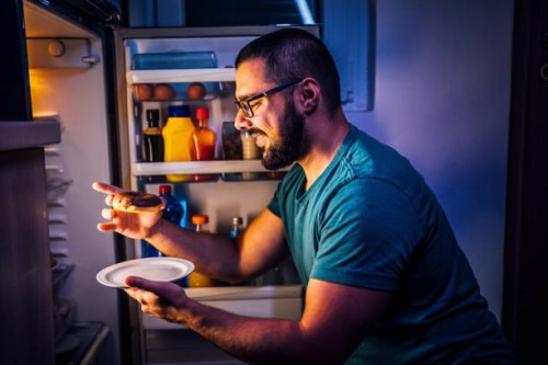 man eats sweets at night - food stock pictures, royalty-free photos & images