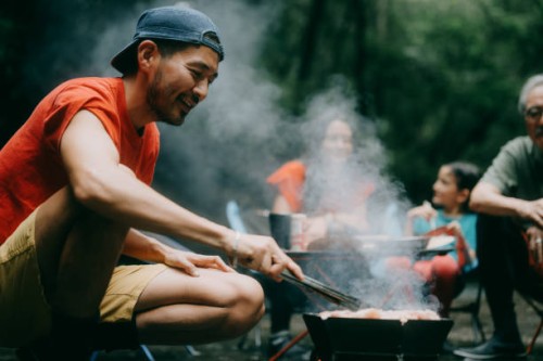 man enjoying bbq with family in nature - food stock pictures, royalty-free photos & images