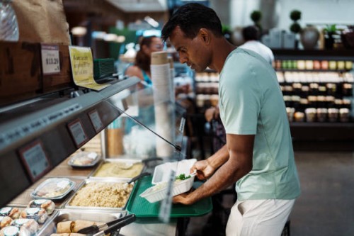 man gets food from a hot food bar at supermarket - junk food stock pictures, royalty-free photos & images