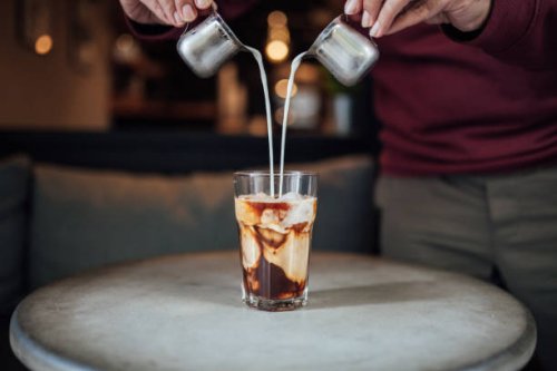 man gieten melk in iced coffee - coffee stockfoto's en -beelden