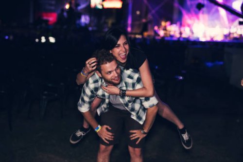 man giving piggy back to his friend in front of the stage - concert stock pictures, royalty-free photos & images