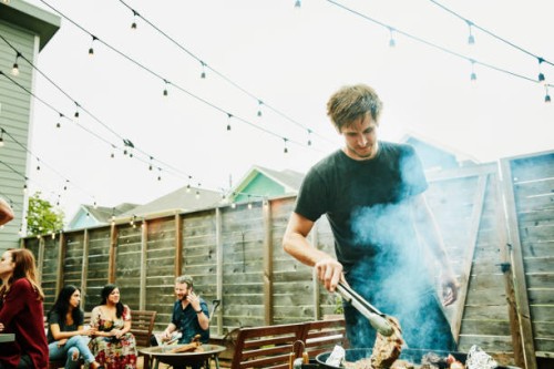 man grilling steaks for friends at backyard barbecue during party - garden decoration photos et images de collection