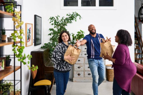 man handing takeaway paper bags to female friends - junk food stock pictures, royalty-free photos & images