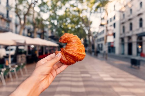 man holding fresh croissant on la rambla street, barcelona, spain - junk food stock pictures, royalty-free photos & images
