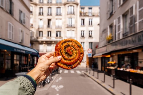 man holding fresh french pastry pain aux raisins on a street in paris, france - food stock pictures, royalty-free photos & images