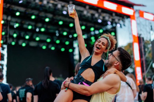 man holding girlfriends in arms at concert - concert stock pictures, royalty-free photos & images